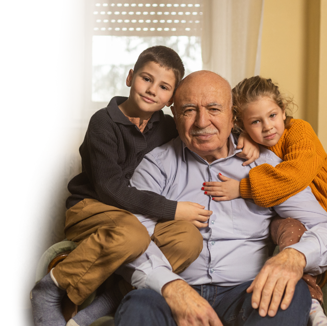 A grandfather sitting with his two grandchildren